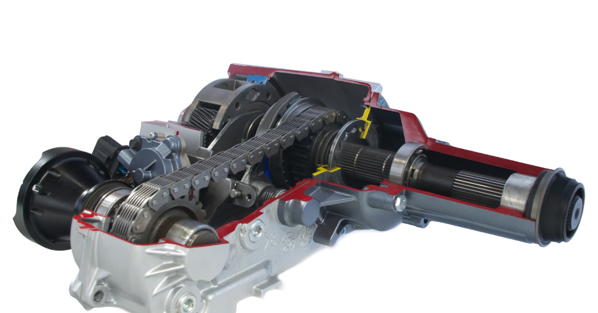 A car's transfer case with a visible chain, gears, and gray housing sits in front of a white studio background.