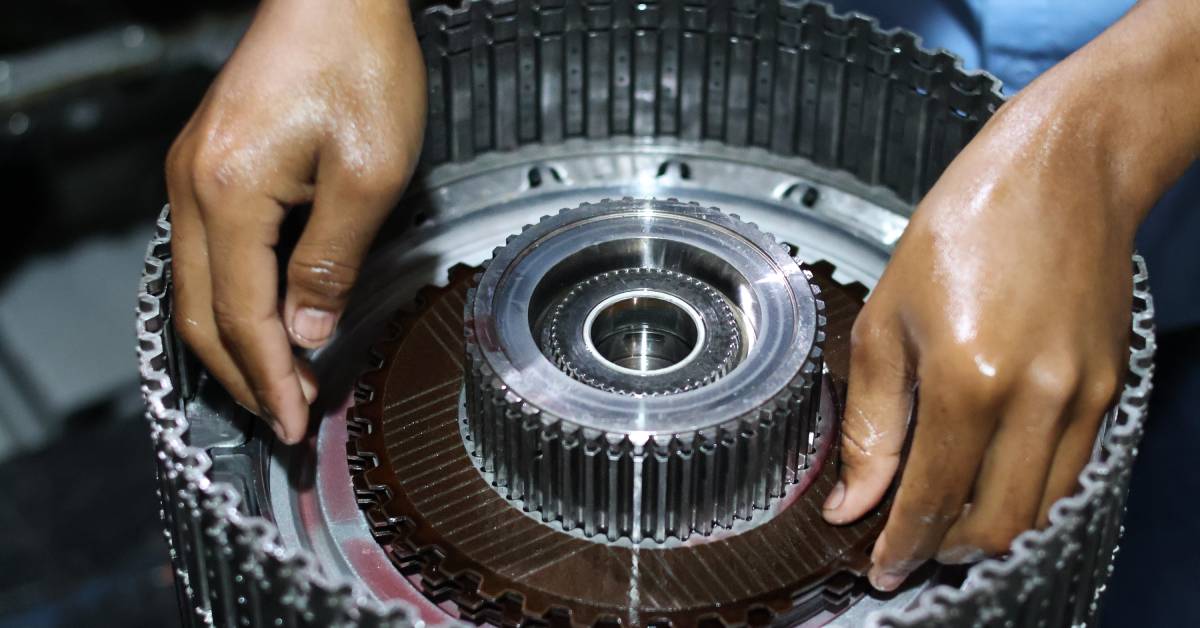Close-up of a person's hands assembling a clutch friction plate on an automatic transmission's clutch pack.